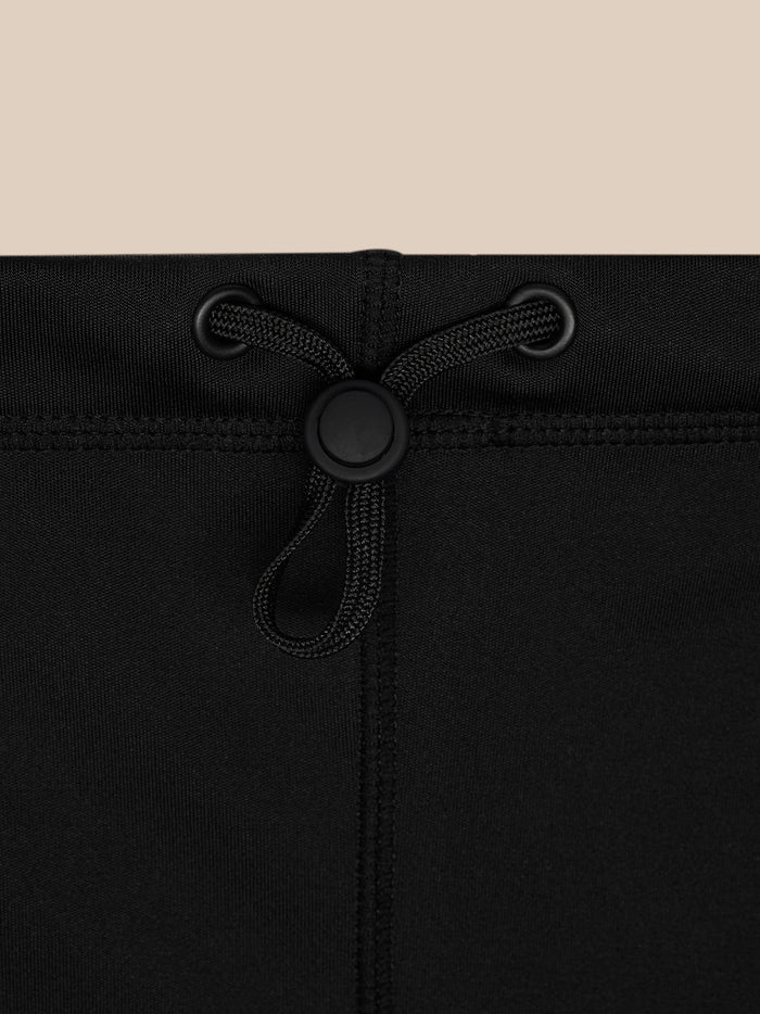 Close-up of a black neck warmer showing a drawstring with eyelets and a cord lock