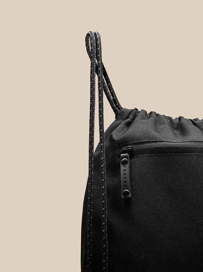 Close up of black Castore gym bag showing braided drawstrings and top opening