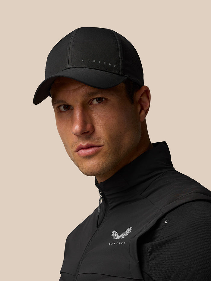 Male model wearing a black Castore cap and jacket with the Castore logo visible on the chest