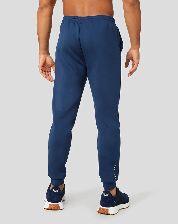 Back view of blue Ore Capsule joggers with elastic cuffs and branding on the lower leg.