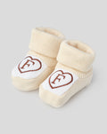 Beige knitted baby booties with folded cuffs and a white toe patch featuring a brown Feyenoord heart logo.