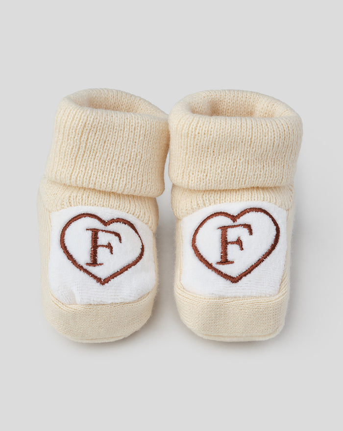 Beige baby booties with white heart patches embroidered with a brown F