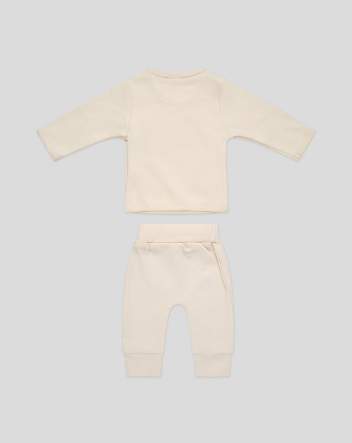 Back view of beige baby top with red trim and matching pants with white drawstring