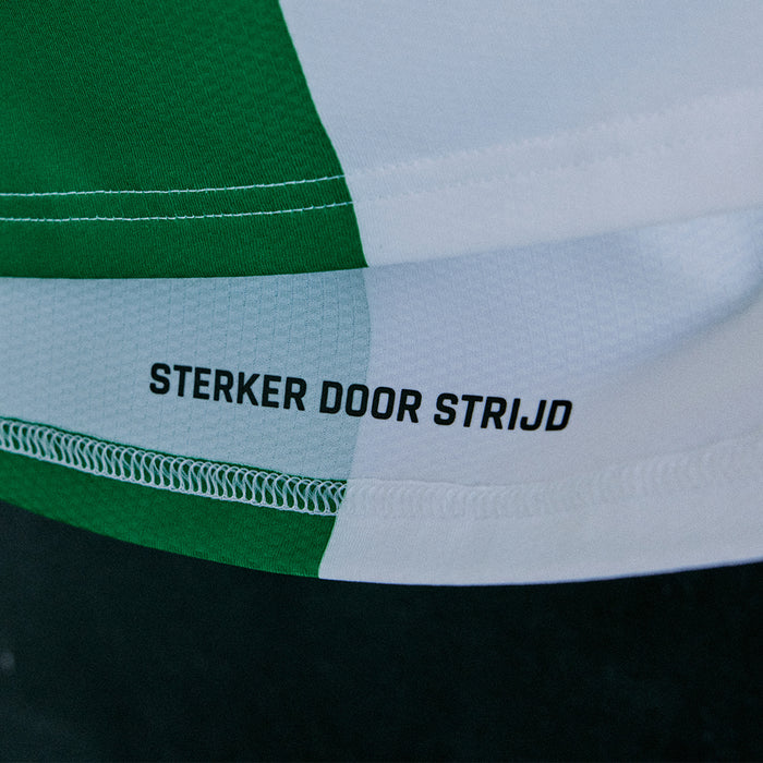 Close-up of the green white panel at the shirt hem with the text STERKER DOOR STRIJD.