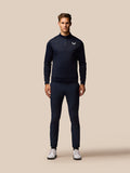 Full body shot of male model in navy Golf Club outfit with zip neck top and matching pants, Castore logo on chest.