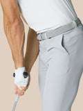Side view of a man wearing light gray golf pants with a braided belt, holding a golf club.