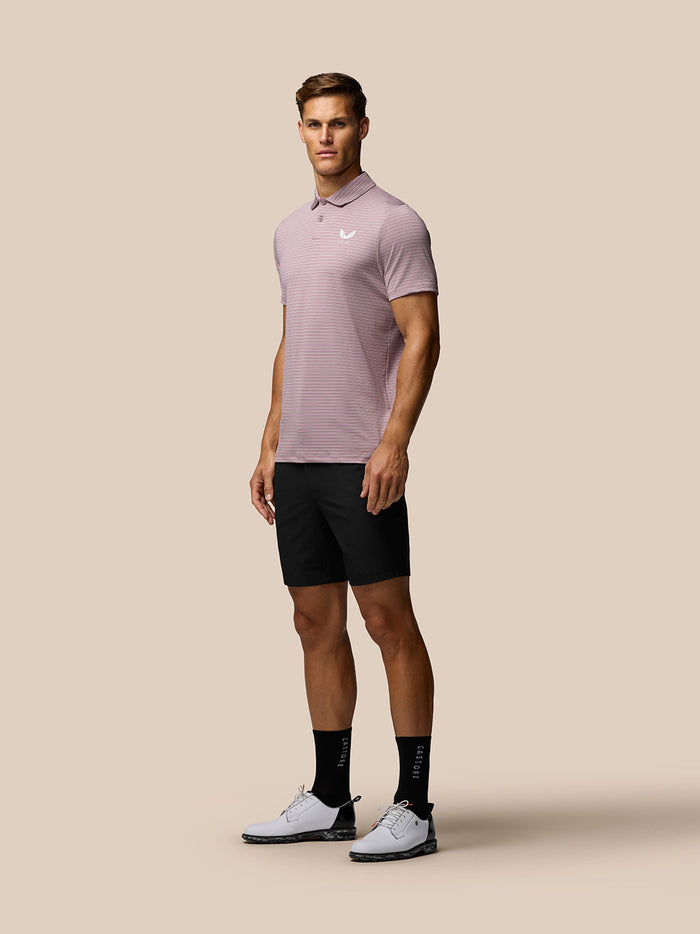Model draagt zwarte Golf Lichtgewicht Short en roze polo, toont pasvorm en zakken.