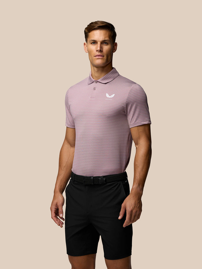 Male model wearing black golf shorts with a belt and a pink striped polo