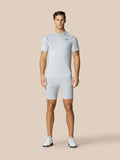 Male model wearing light gray golf polo and matching shorts on a beige background