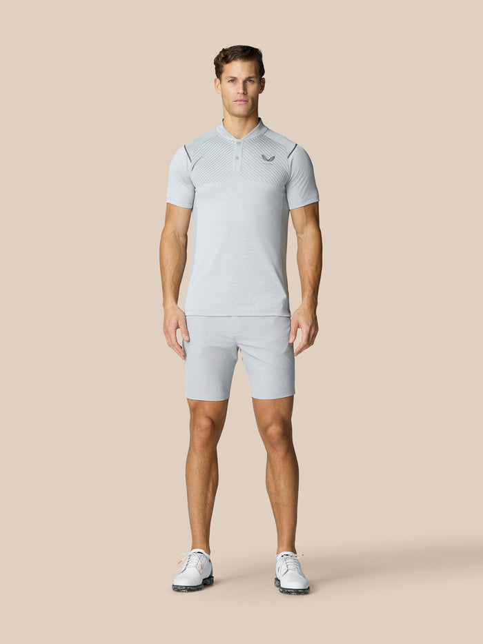 Male model wearing light gray golf polo and matching shorts on a beige background