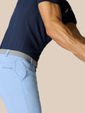 Side view of a golfer in a navy shirt and light blue shorts with a woven gray belt, Castore logo on the hip