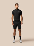 Front view of a man wearing a black Golf Club Essential Polo with Castore branding on the chest, paired with black shorts.