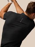Back view of a man wearing a black Golf Club Essential Polo with Castore branding along the back.