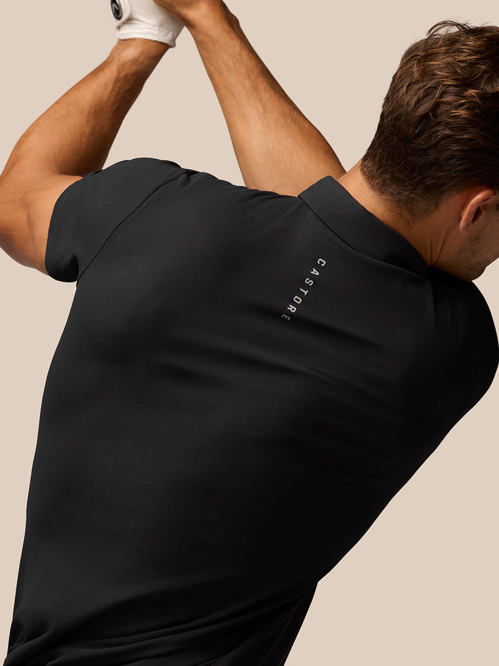Back view of a man wearing a black Golf Club Essential Polo with Castore branding along the back.