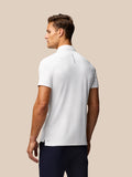 Rear view of white golf polo with vertical Castore branding along the back and Aertek branding near the hem
