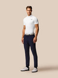 Male model wearing white Golf Essential Polo with Castore logo on chest, paired with navy pants