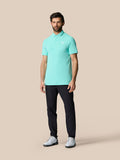 Volledig beeld van man in Licht Aqua Golf Club Essential Polo met korte mouwen donker broek en logo op borst