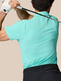 Man draagt Licht Aqua Golf Club Essential Polo gezien van achter met een golfclub over de schouders en Castore logo op de rug
