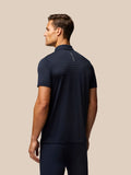 Back view of a man in a navy striped golf polo with a small Castore logo along the upper back