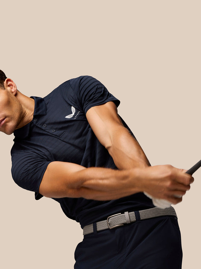 Portrait of a man in navy Pinnacle Pique Stripe Polo with white logo on the chest