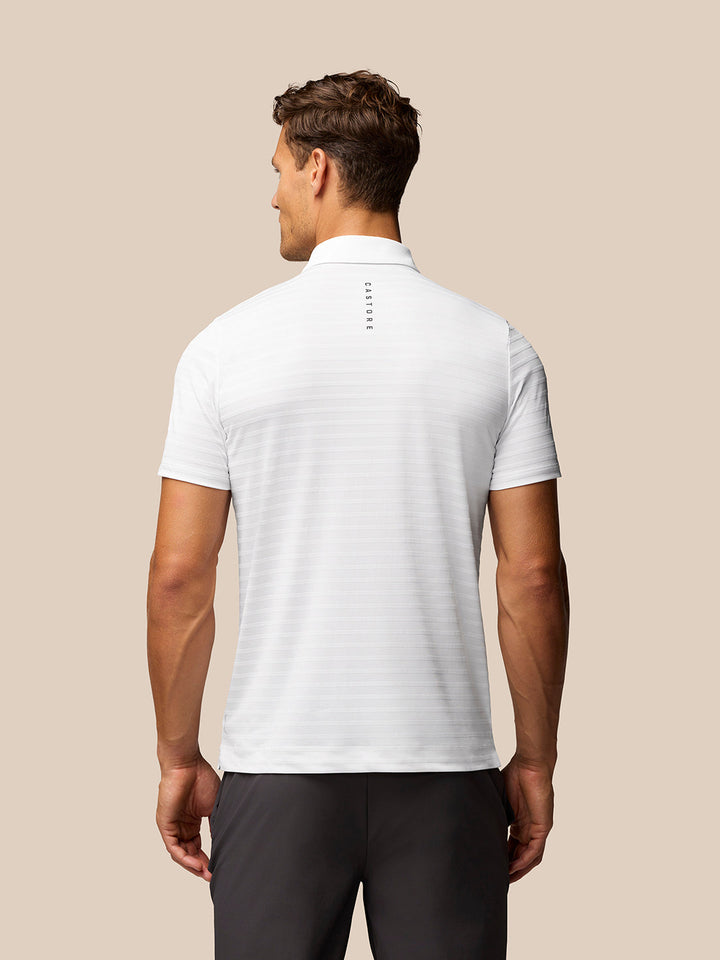Back view of white striped golf polo with vertical Castore branding down the spine