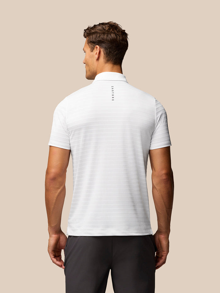 Back view of white striped golf polo with vertical Castore branding down the spine