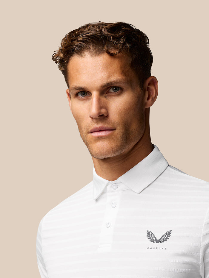 Front view of a male model wearing a white Golf Pinnacle Pique Gestreepte Polo with Castore logo on the chest.