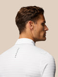 Side profile of a male model in a white Golf Pinnacle Pique Gestreepte Polo with Castore branding down the back.