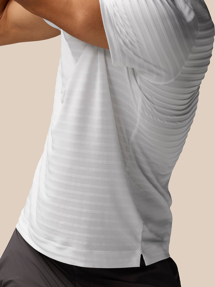 Close-up of back hem showing a small side slit on the white striped polo
