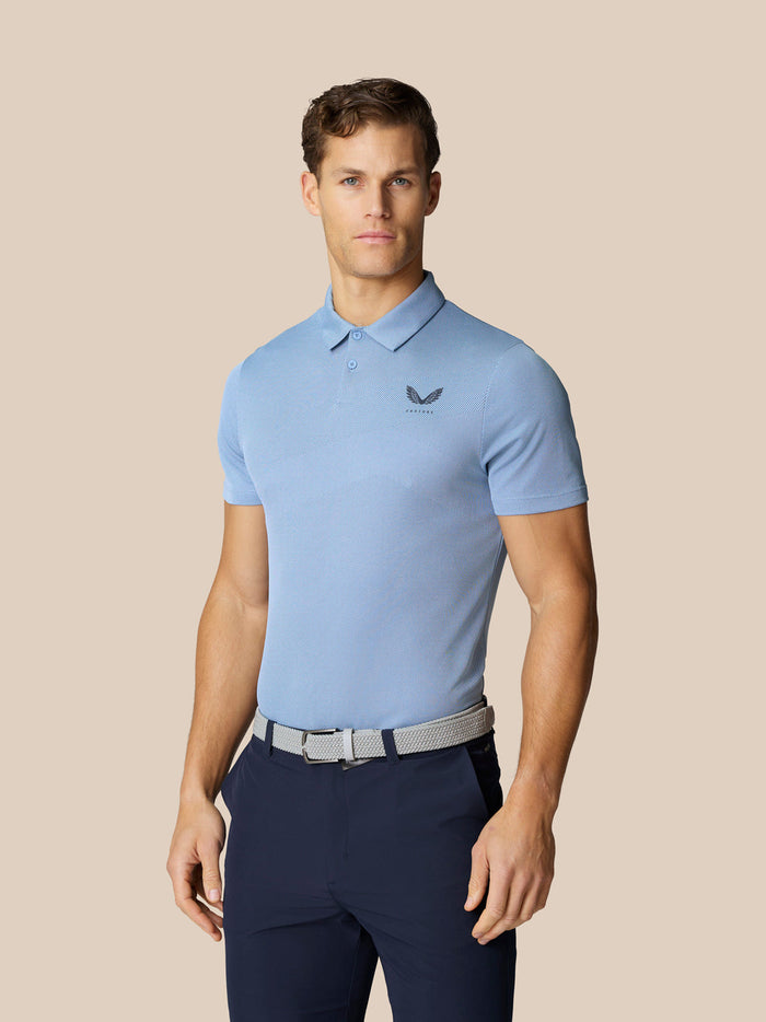 Male model wearing light blue Golf Pinnacle Polo with short sleeves and dark trousers.