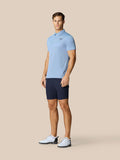 Full body shot of a man in the Golf Pinnacle Polo Hemelsblauw with navy shorts, showing a lightweight breathable polo on the course
