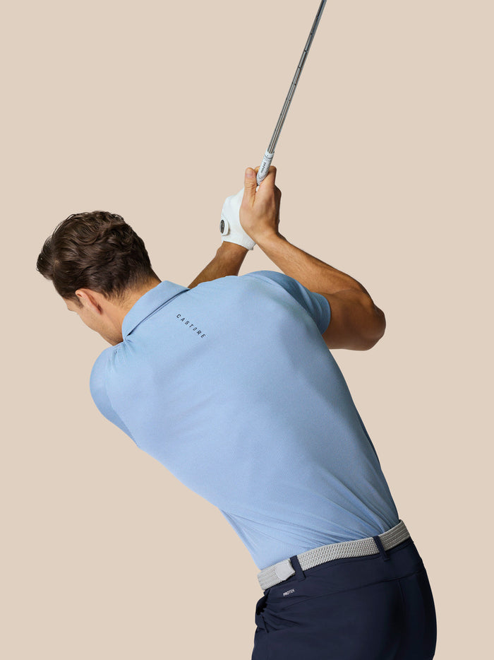 Golfer in een hemelsblauwe Golf Pinnacle Polo tijdens een swing, met ademende gebreide stof en bewegingsvrijheid.