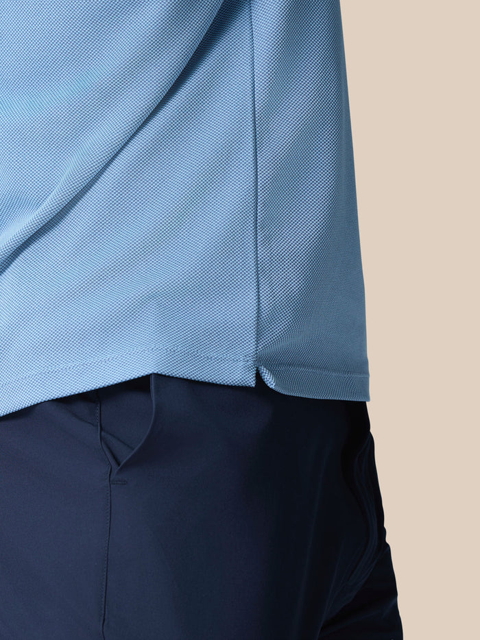 Close up of the light blue knitted fabric showing the textured weave and hem edge of the Golf Pinnacle Polo