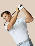 Male model in a white Golf Pinnacle Polo swinging a golf club, showing a side angle with light blue pants and a gray belt.