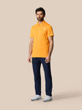 Full-body shot of a man in a Mango Golf Pinnacle Polo with navy pants and white sneakers.
