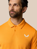 Front view of a man in a Mango orange polo with a polo collar and a white Castore logo on the chest.