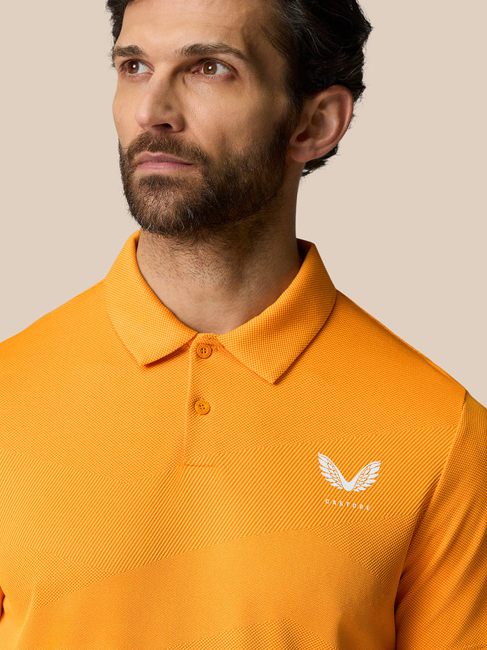 Front view of a man in a Mango orange polo with a polo collar and a white Castore logo on the chest.