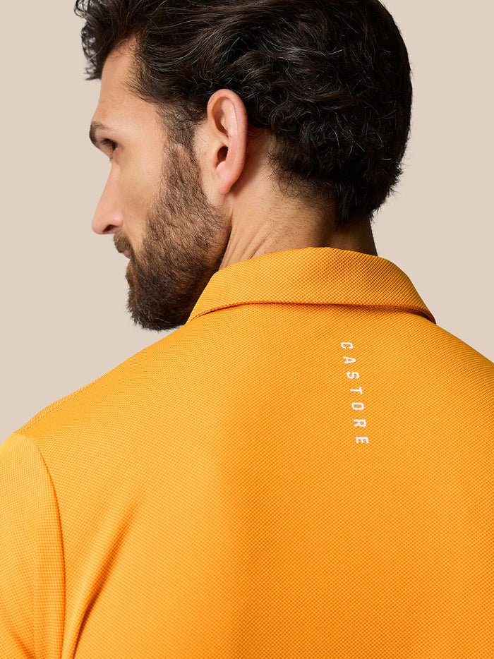 Back view of a man wearing a Mango Golf Pinnacle Polo with a Castore logo on the upper back.