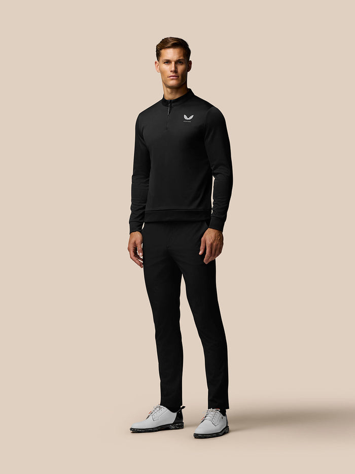 Full body shot of a man in a black Golf Club classic top with a quarter zip, Castore branding on chest and upper back.