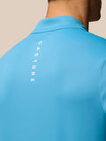 Back view of bright blue golf top with vertical CASTORE branding along the upper back.