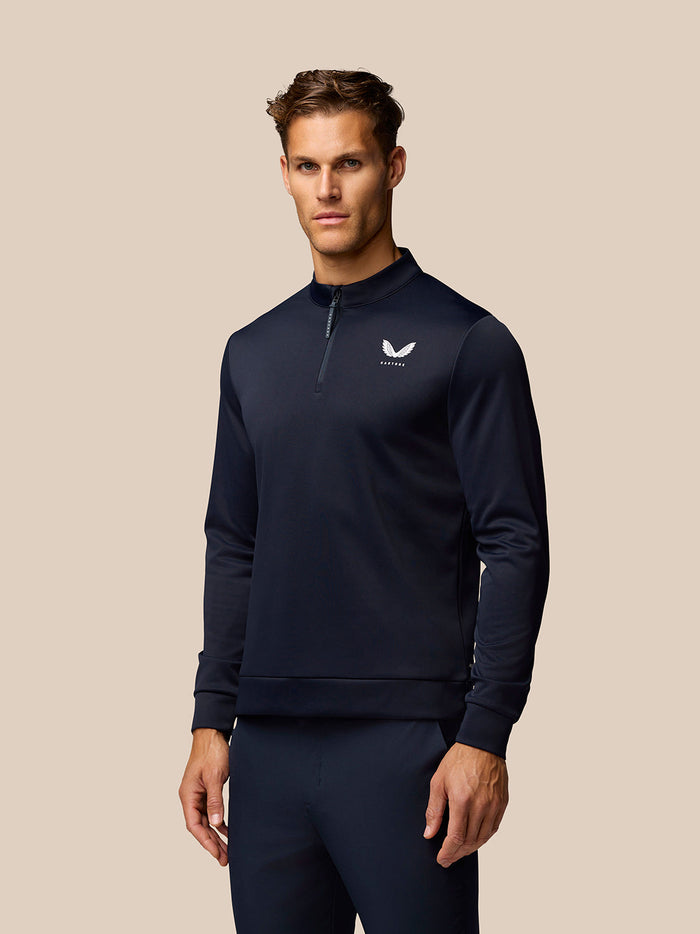 Male model wearing navy Golf Club Classic quarter zip top with stand collar and long sleeves Castore logo on the chest.