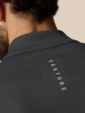Back view of a dark golf top with a high collar and a zipper pull branded Castore
