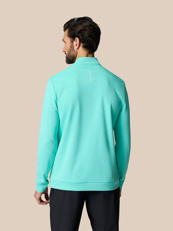 Back view of a man wearing the aqua golf top with Castore branding running across the upper back.