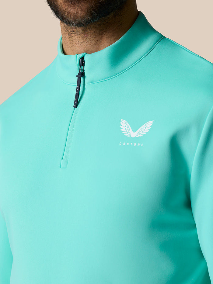 Close-up of a light aqua golf top with stand-up collar and quarter zip, Castore logo on the chest.
