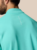 Back view of a light aqua golf top with the Castore logo along the upper back.