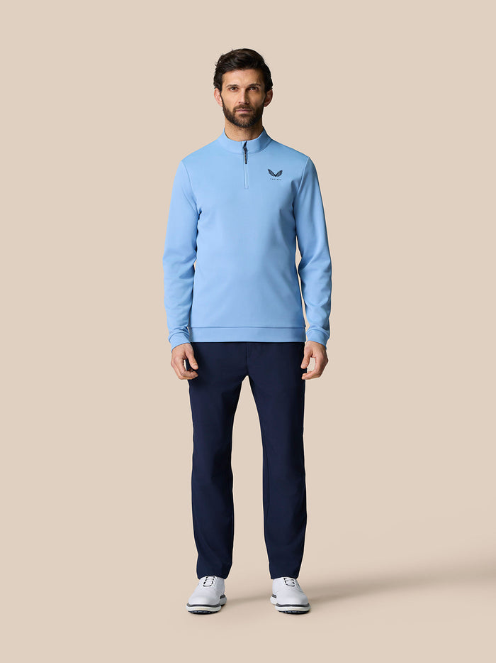 Light blue Golf Club Classic Quarter Zip Top on a male model featuring a stand collar, long sleeves, Protek water resistance, and Castore logo on chest.