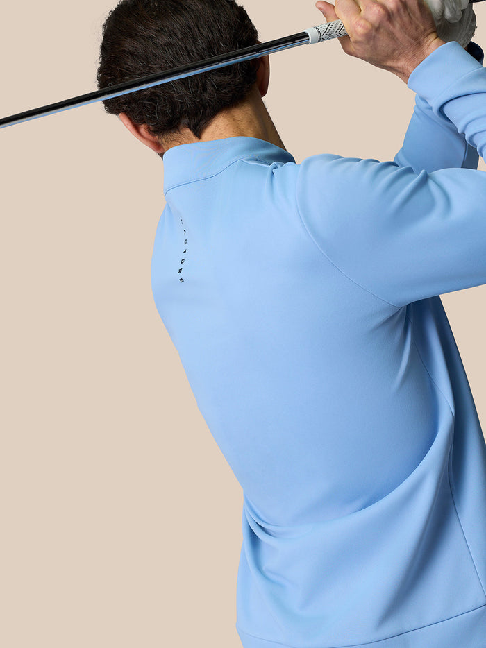 Back view of a golfer wearing a light blue Club Classic Quarter Zip Top with CASTORE logo down the back