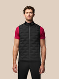Man wearing a black padded sleeveless gilet with a stand up collar over a bright pink short sleeve shirt, showing quilted panels.