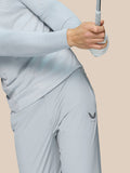 Full-body view of a male model in light gray golf outfit standing with a club, Castore logo visible on the right thigh