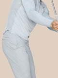 Side view of a male model wearing light gray golf pants with Castore logo on the right thigh, holding a golf club